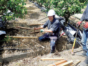 矢野智徳さん（62歳）。木杭を使って雨水の流れを停滞させ、浸透を促す抵抗柵づくりを指導する