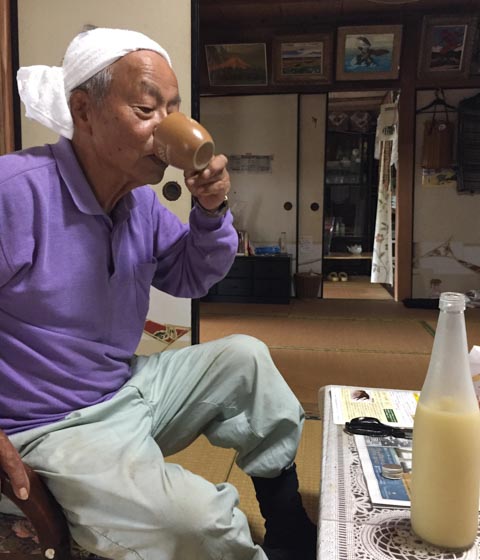 私がつくったアワの神酒を飲む竹本真良さん（小浜島）