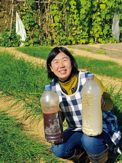 菌液を持つ筆者。赤いほうは光合成細菌、白いほうは乳酸菌（写真はp39以外、編集部撮影）