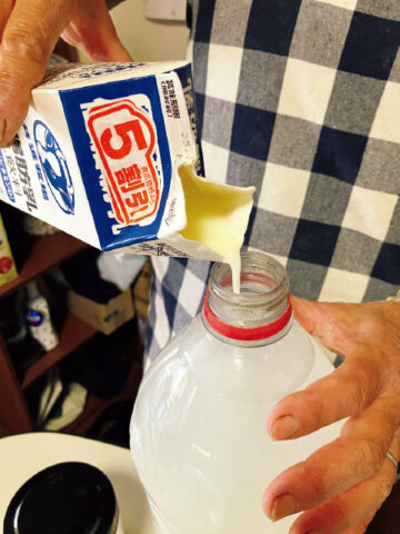 台所に4Lのペットボトルを置いておき、米のとぎ汁と、ヨーグルトや牛乳、豆乳などの容器を洗った液を随時入れる。満杯になる前に低脂肪乳（写真）を足してカルシウム補給。砂糖も入れて発酵させる