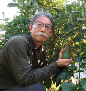 筆者（65歳）。ひょうたん型でかわいい「ピンカートン」の果実とともに